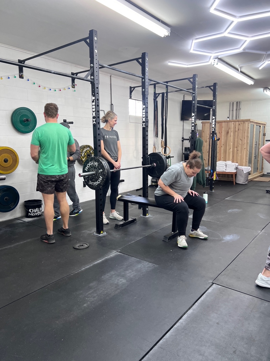 Coach spotting a member during bench press at South Fork Gym